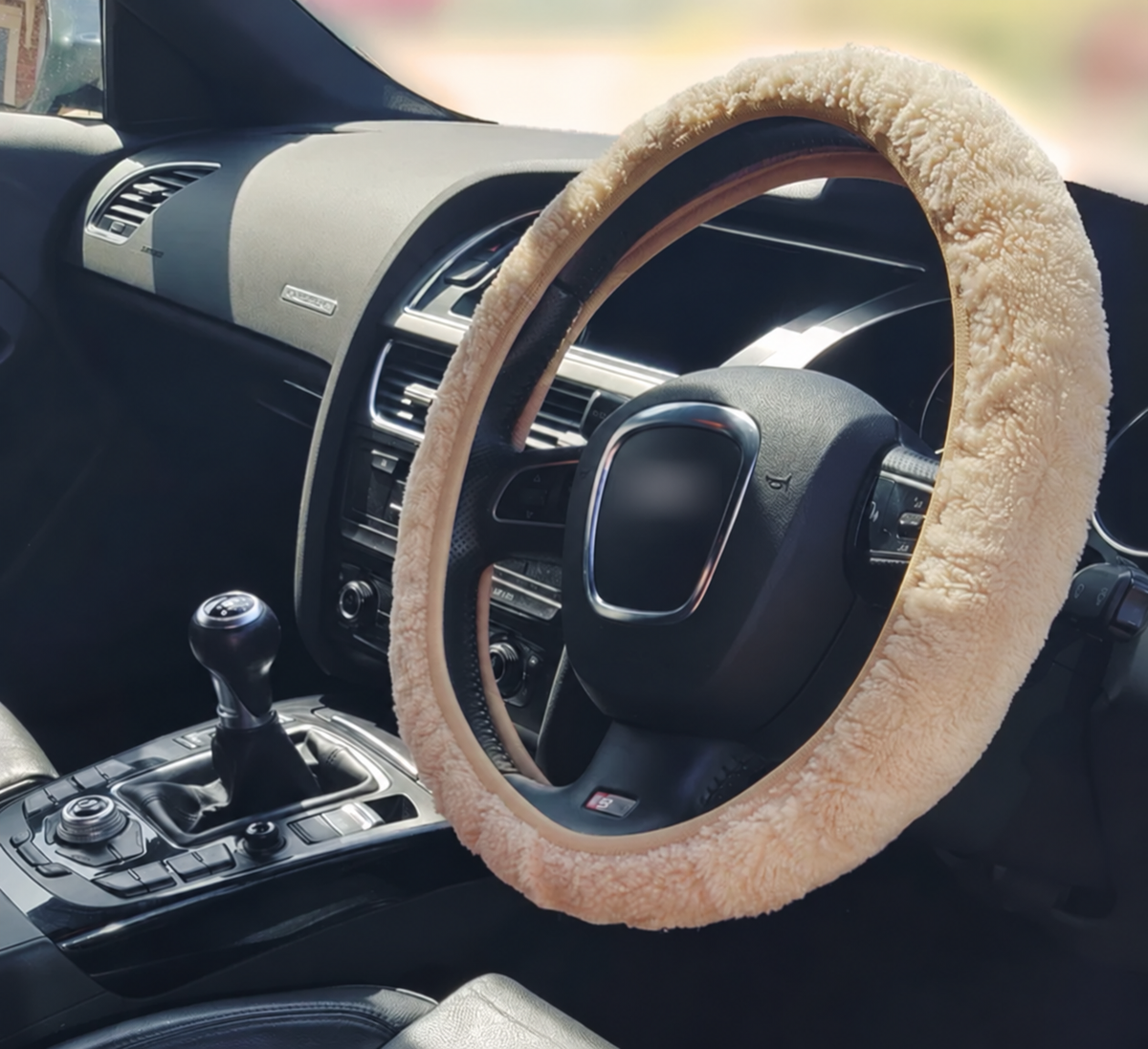 Beige sheepskin steering wheel cover with soft plush texture and fitted inner opening