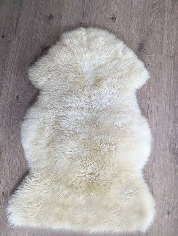 Natural ivory sheepskin rug top view showing uneven plush shag pile